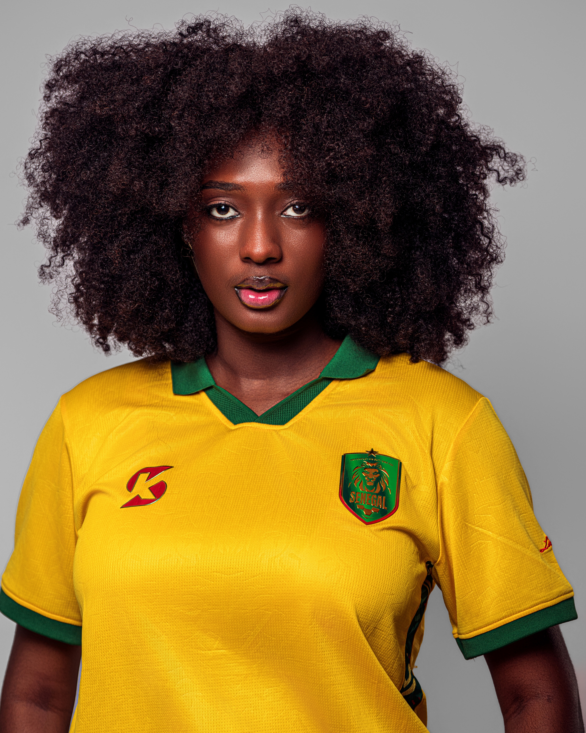 01 Maillot de football jaune vif du Sénégal, col polo vert, avec logo et motifs latéraux.