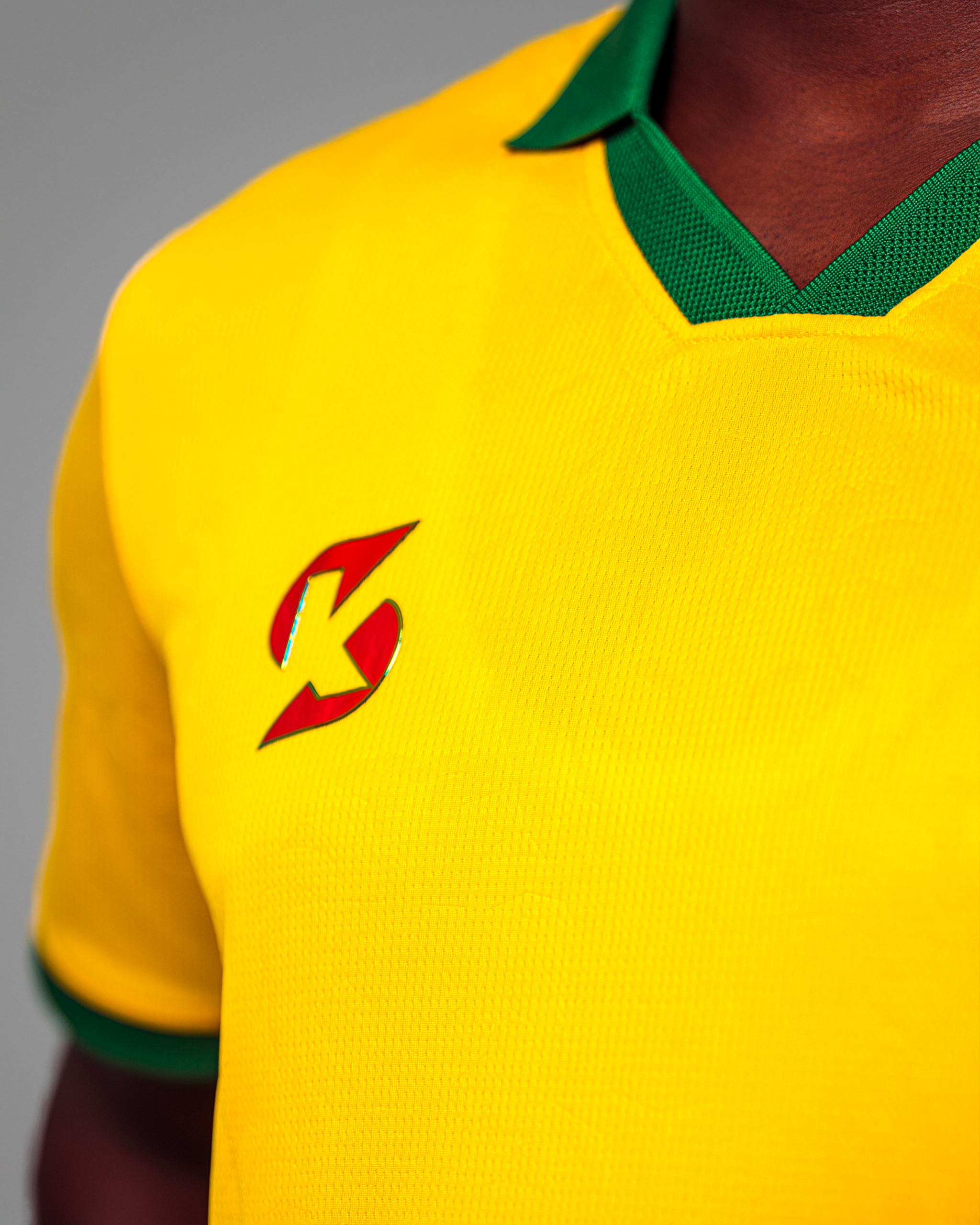 03 Maillot de football jaune vif du Sénégal, col polo vert, avec logo et motifs latéraux.