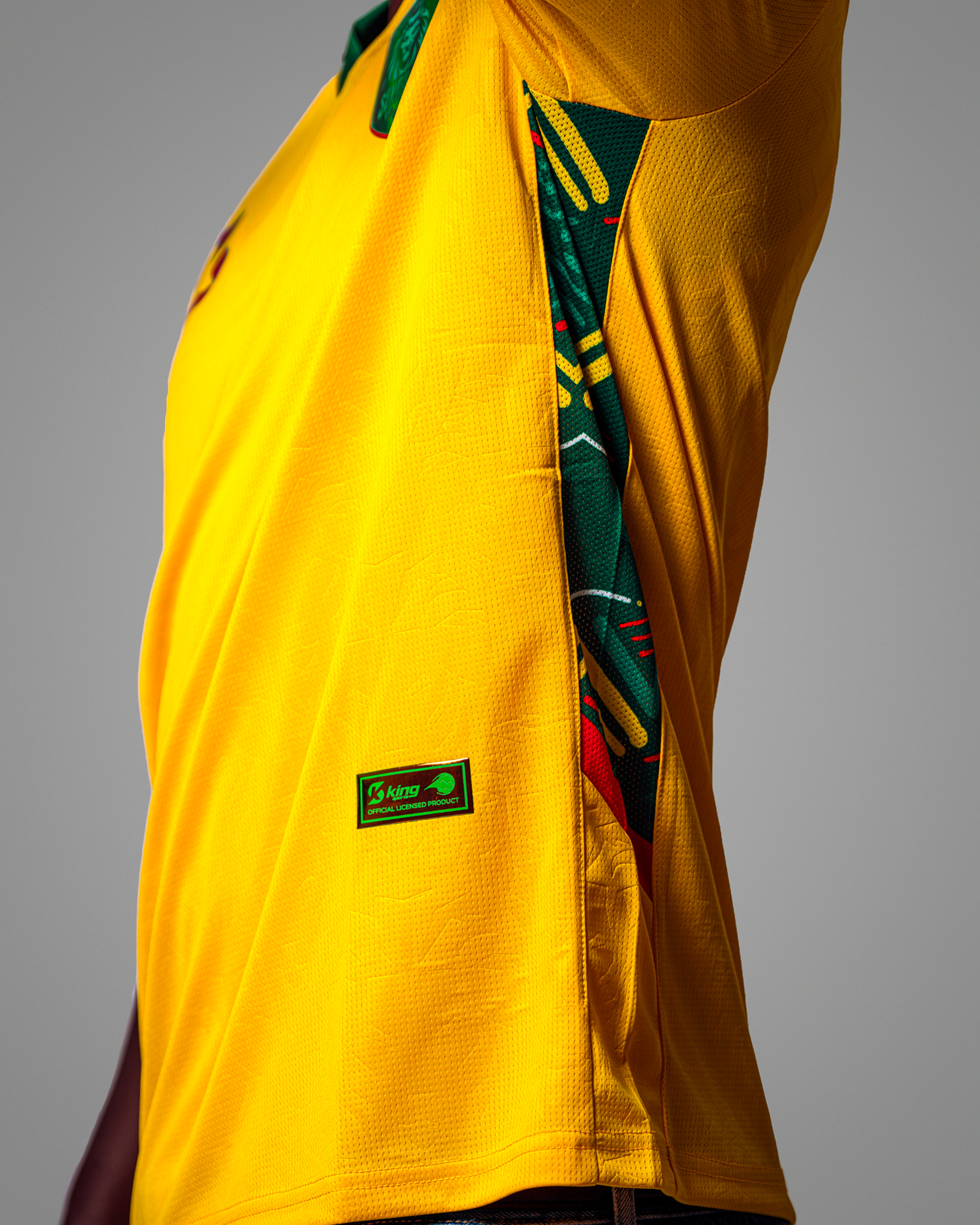05 Maillot de football jaune vif du Sénégal, col polo vert, avec logo et motifs latéraux.
