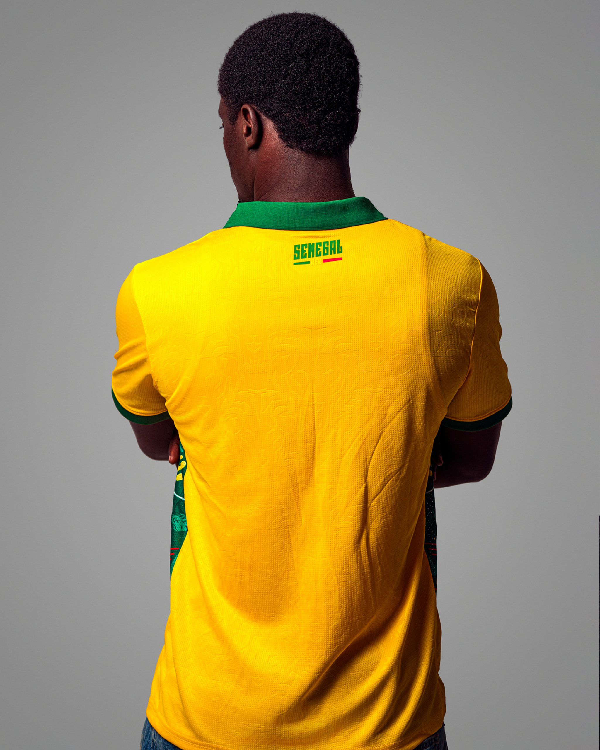 06 Maillot de football jaune vif du Sénégal, col polo vert, avec logo et motifs latéraux.